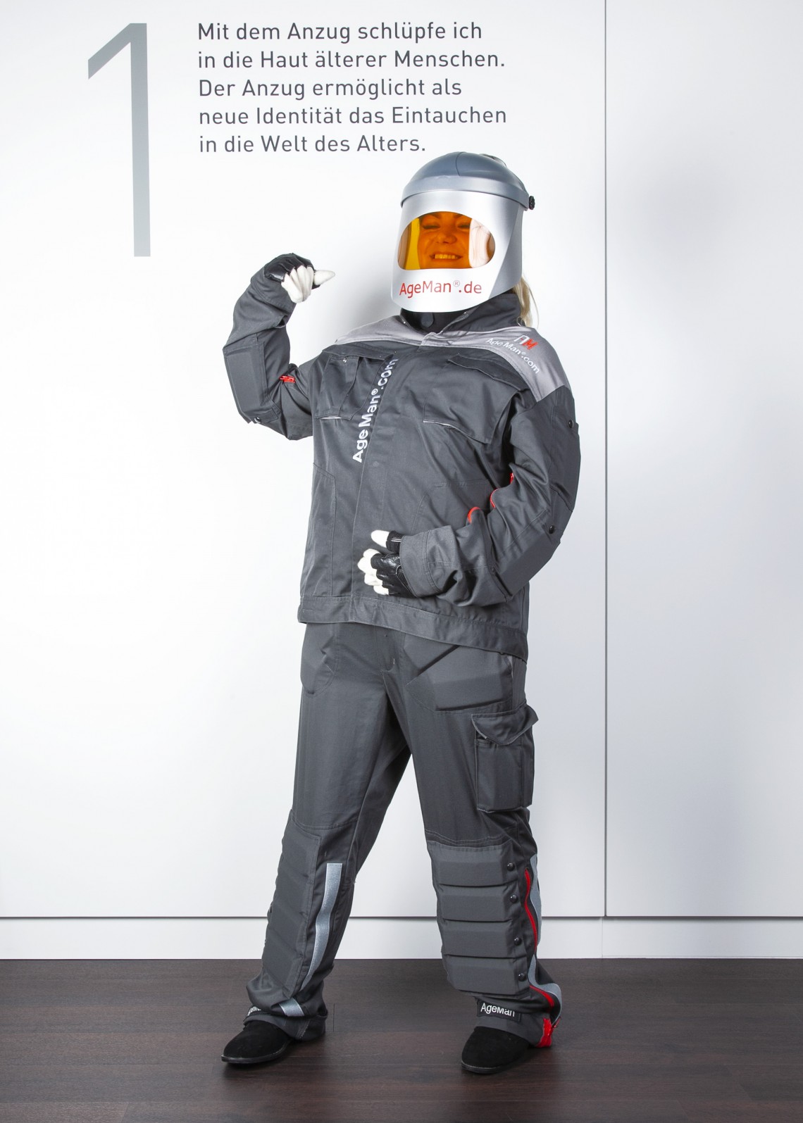 Junge Frau mit angelegtem AgeMan Alterssimulationsanzug am Startpunkt des Selbsterfahrungs-Parcours