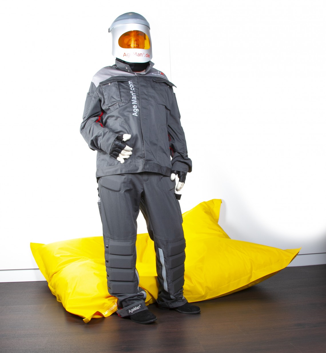 Junge Frau mit angelegtem AgeMan Alterssimulationsanzug stehend nach Aufstehen von einem Fatboy Sitzkissen - Phase 4