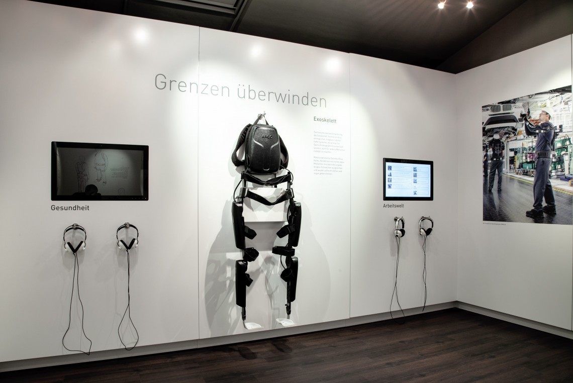 Blick auf eine Präsentationswand mit Monitoren und wandmontiertem Exoskelett mit Markenname „ReWalk“ zur Wiedererlangung der Eigenmobilität bei Querschnittslähmungen