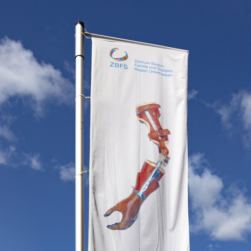 Große Fahne mit Würzburger-Prothesensammlung Second Hand Logo im Außenbereich vor dem Eingang zur Prothesensammlung
